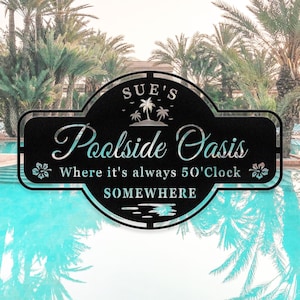 Puede incluir: Señal de metal negro con el texto "Sue's Poolside Oasis Where it's always 5 o'clock Somewhere". La señal está decorada con palmeras y flores.