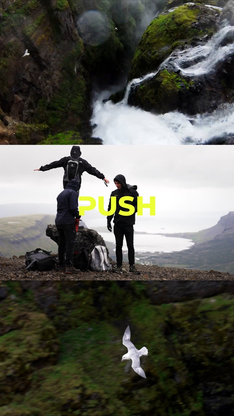 May include: Three people stand on a rocky cliff overlooking a body of water. The person in the middle is wearing a black jacket and has the word "PUSH" written in yellow letters on their chest. The sky is overcast and the water is a light blue color.