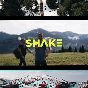 May include: Two people walking in a grassy field with mountains in the background. The word "SHAKE" is written in yellow letters across the image.
