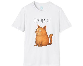 May include: White t-shirt featuring a cartoon orange cat with wide eyes and the phrase "FUR REAL?!" above it. The cat is sitting and has a curved tail. The shirt has a crew neck.