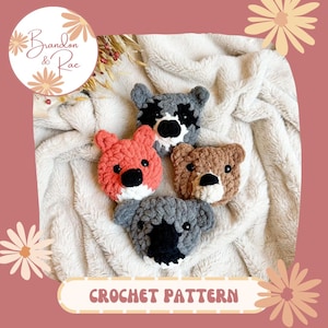 Könnte beinhalten: Vier gehäkelte Tierkopf-Plüschtiere in verschiedenen Farben: ein grauer Waschbär, ein orangefarbener Fuchs, ein brauner Bär und ein grauer Koala. Die Plüschtiere liegen auf einer weißen, flauschigen Decke. Häkelanleitung.