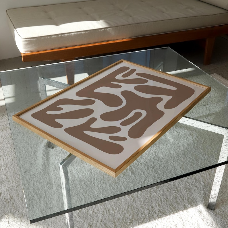 May include: A framed abstract print with a brown and white design. The print features a series of organic shapes that resemble abstract forms.