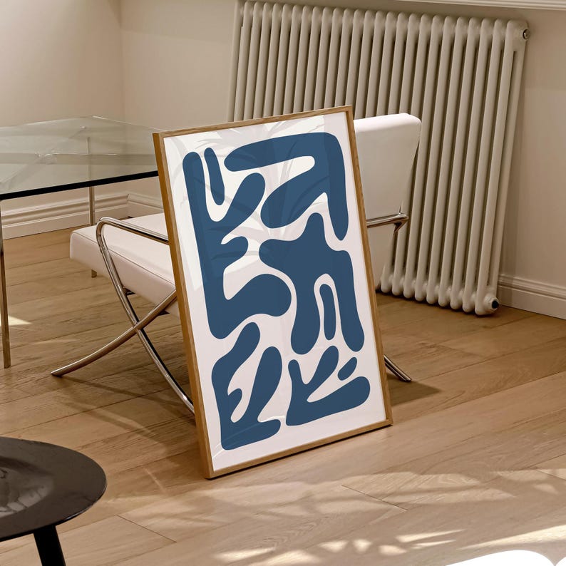 May include: A framed abstract print with a white background and blue abstract shapes. The print is in a wooden frame.