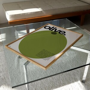 May include: A framed print featuring a large green circle and the word "olive." in black text. The print has a white background and a wooden frame.