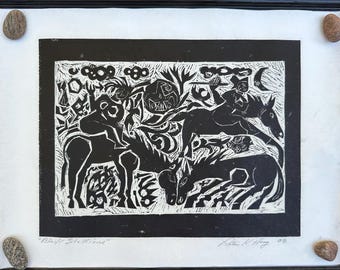 May include: Black and white linocut print titled "Black Stallions" depicting figures on horseback and in a landscape. The artwork is framed in black and mounted on white paper, with small stones in each corner.