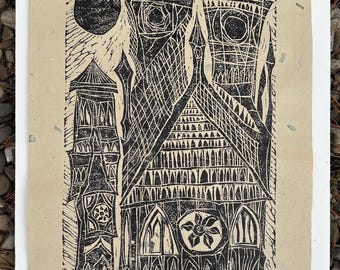 May include: Black and white linocut print depicting a stylized architectural scene with towers, arches, and a central building featuring a floral motif. A dark circle represents the sun. The print is on textured, off-white paper.