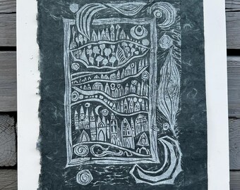 May include: A framed, dark teal print with a white border. The print features a detailed, stylized cityscape in white, including buildings, trees, and celestial elements. The artwork is mounted with pins on a white backing.