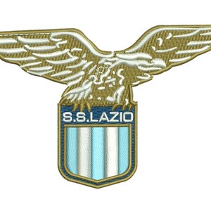 May include: Embroidered patch of the S.S. Lazio emblem. The design features a golden eagle above a shield with the text "S.S. LAZIO" and light blue and white stripes. The patch has a detailed, textured appearance, suitable for clothing.