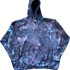 May include: A long-sleeve hooded sweatshirt featuring a tie-dye pattern in shades of dark purple, navy blue, and light blue. The garment includes a front kangaroo pocket, a hood with white drawstring cords, and ribbed cuffs at the sleeves.