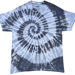 May include: A short-sleeved t-shirt featuring a spiral tie-dye pattern in shades of charcoal grey, slate blue, and white. The garment has a crew neckline and a standard fit, with the tie-dye design radiating from the centre of the chest outwards.