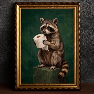 Puede incluir: Una obra de arte enmarcada que presenta un mapache sosteniendo un rollo de papel higiénico. El mapache, con pelaje detallado, está posado sobre un bloque verde contra un fondo verde oscuro. El marco es dorado.