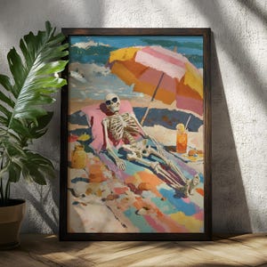 May include: A framed art print depicts a skeleton relaxing on a beach under a striped umbrella. The skeleton wears sunglasses and is lounging on a colorful beach towel. A drink with a straw and a small jar are also visible. The artwork is framed in a dark wooden frame.
