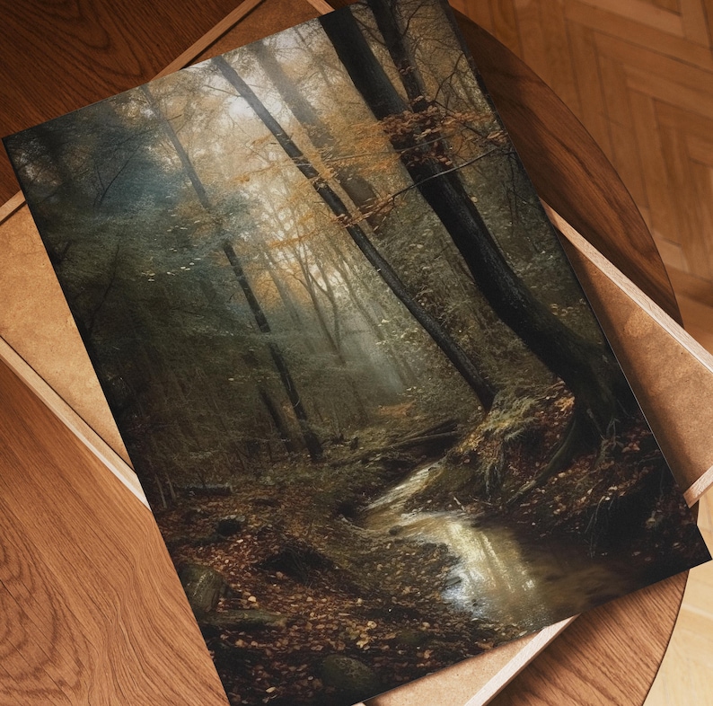 May include: A framed print depicting a forest scene. The image shows tall trees with brown and green foliage, a small stream, and a misty atmosphere. The print is presented in a wooden frame, with a cardboard backing.