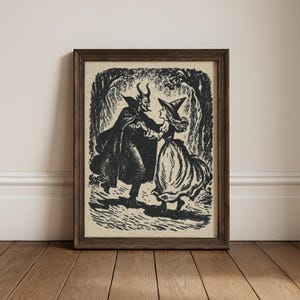 May include: Framed black and white print showing a devil and a witch dancing in a forest setting. The devil is wearing a cape and has horns, while the witch wears a pointed hat and a long dress. The artwork is in a vintage style.