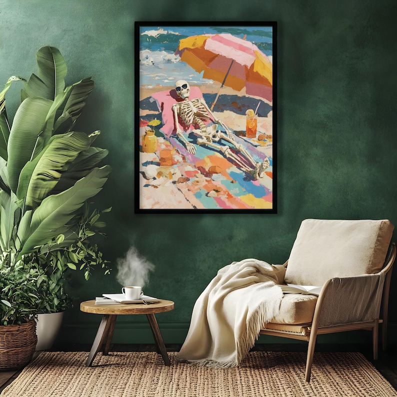 May include: A framed art print depicts a skeleton sunbathing on a beach under a striped umbrella. The artwork features vibrant colors, including blue, pink, yellow, and orange. The skeleton wears sunglasses and is lounging on a colorful beach towel.