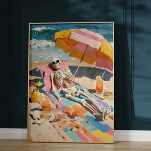 May include: A framed art print depicts a skeleton relaxing on a beach. The skeleton wears sunglasses and is under a striped umbrella. A colorful beach scene with a drink and small umbrellas is also visible.