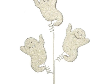 May include: Three glittery white ghost decorations on a white stem with silver wire accents. Each ghost has a smiling face and outstretched arms, perfect for Halloween or spooky-themed decor.