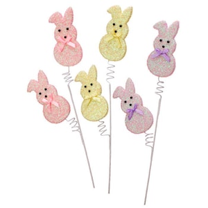 May include: Glittery Easter bunny decorations in shades of pink and yellow, each with a small bow and black bead eyes. The bunnies are attached to silver wire stems, perfect for spring crafts and Easter decor.