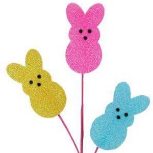 May include: Three glittery Easter bunny decorations in yellow, pink, and blue. Each bunny has black dot eyes and is attached to a pink wire stem. The bunnies are in a close-up shot against a white background.