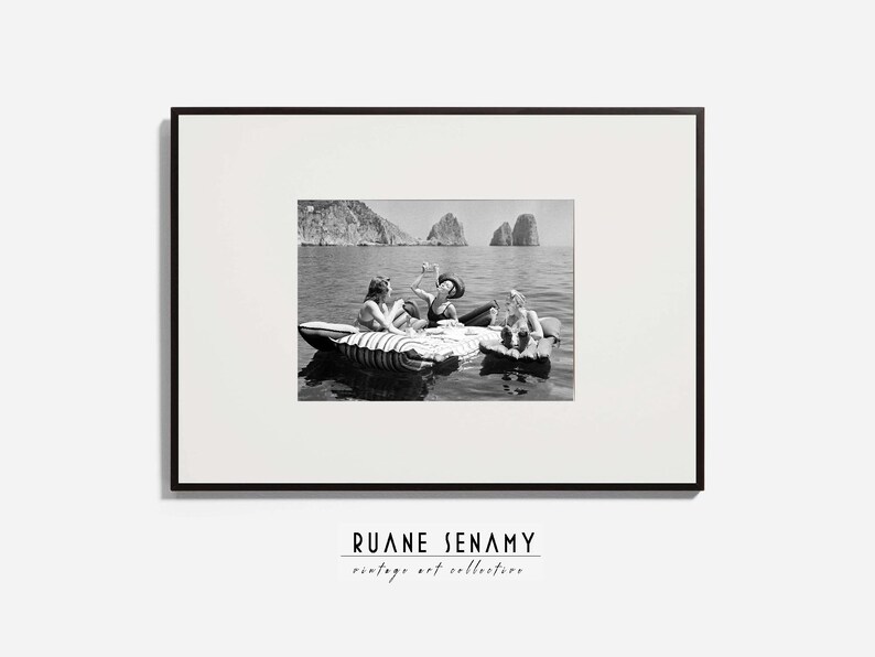 Peut inclure: Photographie en noir et blanc de trois personnes sur un radeau dans l'eau. Les personnes sourient et semblent s'amuser. La photo est encadr&eacute;e dans un cadre noir.