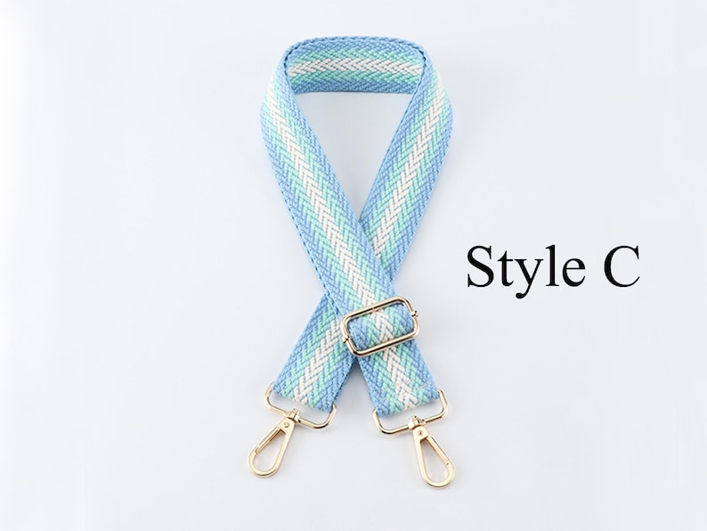 K&ouml;nnte beinhalten: Ein gewebter Taschenriemen in hellblau und wei&szlig; mit goldenen Beschl&auml;gen. Der Riemen ist in der Mitte gefaltet und die Enden des Riemens sind mit goldenen Verschl&uuml;ssen verbunden. Der Text "Style C" ist auf dem Bild zu sehen.