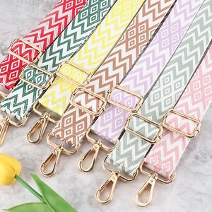 May include: Seven colorful patterned straps with gold metal clasps. The straps have a zig-zag pattern and are made of woven fabric.