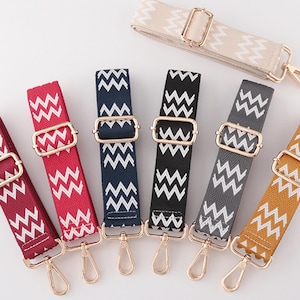 May include: A selection of patterned bag straps in shades of red, navy, black, grey, and yellow. Each strap features a white zigzag design and gold-coloured metal fixings, including buckles and clasps.