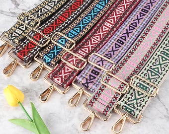 May include: A collection of colorful, patterned bag straps with gold-colored metal hardware. The straps feature geometric designs in various colors, including red, blue, and green. Each strap has a gold clasp for easy attachment.