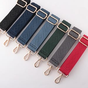May include: Seven adjustable bag straps in various colors: black, navy, denim, teal, forest green, gray, and red. Each strap features a diamond pattern, gold-tone hardware, and a swivel clasp for easy attachment.