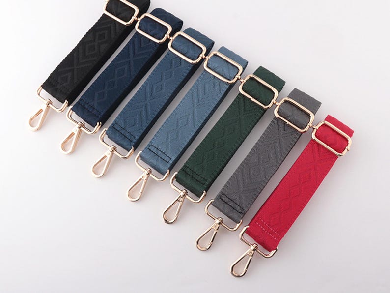 May include: Seven adjustable bag straps in various colors: black, navy, denim, teal, forest green, gray, and red. Each strap features a diamond pattern, gold-tone hardware, and a swivel clasp for easy attachment.