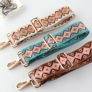 Puede incluir: Tres correas de tela con estampado y cierres de metal dorado. Las correas son de color beige, turquesa y marrón con un diseño geométrico.