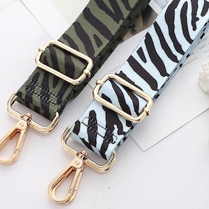 May include: Two adjustable straps with gold metal clasps. One strap is green with a black zebra print and the other is light blue with a black zebra print.