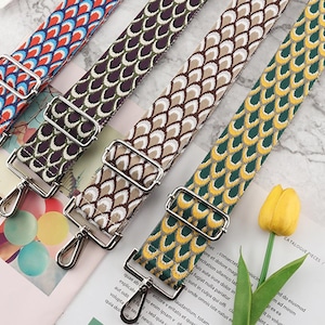 May include: Four adjustable bag straps featuring a repeating scale pattern in blue, red, and white; dark purple and white; beige and white; and green and yellow. Each strap includes silver-toned metal hardware, including a sliding buckle and swivel clips.