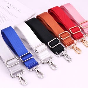 Pode incluir: Oito correias ajustáveis de diferentes cores com fechos giratórios prateados. As correias são feitas de tecido tecido e estão disponíveis em branco, azul, preto, castanho, vermelho, rosa e dois tons de cinza.