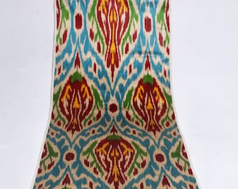 May include: A colorful fabric with a repeating pattern of blue, red, yellow, and green. The fabric has a white background and a woven texture.