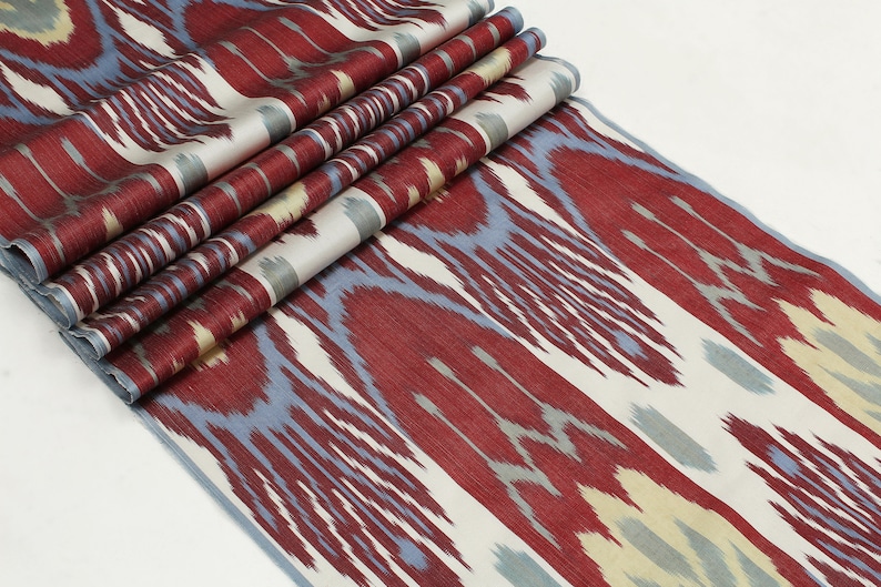 Pu&ograve; includere: Tessuto ikat rosso, blu e bianco con un motivo ripetitivo. Il tessuto &egrave; piegato in pi&ugrave; strati.