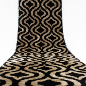 May include: Black and gold fabric with a geometric pattern. The fabric has a raised texture and a luxurious feel.