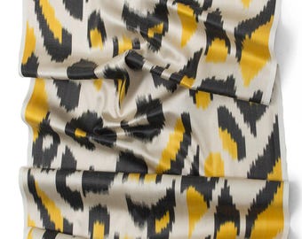 May include: A close-up of a fabric with a black and yellow animal print pattern. The fabric is a silky material and has a subtle sheen.