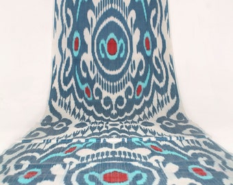 Peut inclure: Un tissu blanc avec un motif ikat bleu et turquoise. Le motif présente un dessin répétitif de cercles et de volutes. Le tissu a un léger brillant et une texture douce.