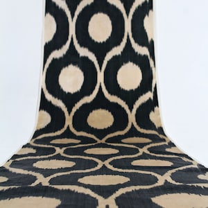 Può includere: Tessuto ikat nero e beige con un motivo ripetitivo di cerchi e volute.