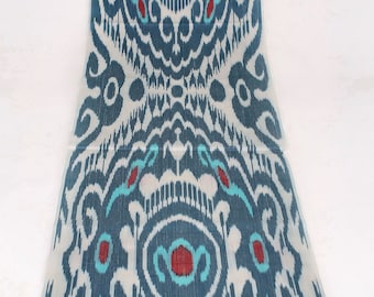 May include: A close-up of a blue and white fabric with a repeating pattern of stylized flowers and swirls. The fabric has a subtle sheen and a soft texture.