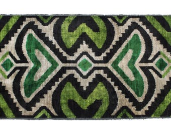 Könnte beinhalten: Ein grüner und schwarzer Teppich mit geometrischem Muster. Der Teppich hat einen dezenten Glanz und eine weiche Textur.