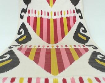 May include: A white fabric with a repeating pattern of pink, red, and yellow stripes. The stripes are arranged in a chevron pattern, creating a geometric design. The fabric has a subtle sheen and a soft texture.