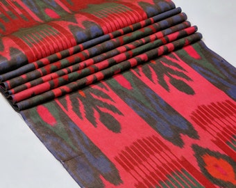 Könnte beinhalten: Ein gefalteter Stoff mit einem Ikat-Muster in Rot, Blau, Grün und Braun.