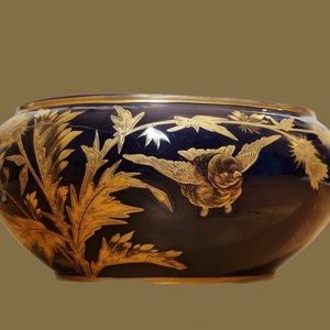 May include: A dark blue ceramic bowl with gold painted floral and bird designs.