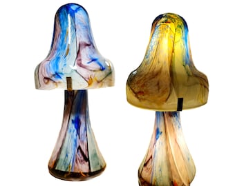 May include: Two glass mushroom lamps with colorful swirls. The lamp on the left is blue, green, and purple. The lamp on the right is yellow, orange, and brown.