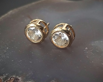 May include: A pair of gold stud earrings with clear round gemstones.