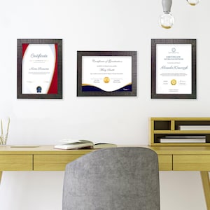 May include: Three framed certificates with black frames and white mounts hanging on a white wall. The certificates have black text on white paper with a gold seal. The certificates are titled "Certificate", "Certificate of Graduation", and "Certificate of Recognition".