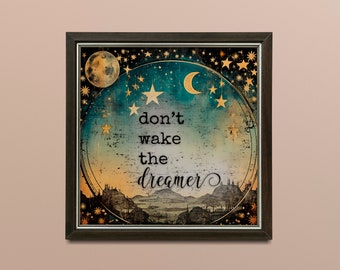 May include: Framed art print with a celestial design. It features a moon, stars, and the text "don't wake the dreamer." The artwork has a vintage aesthetic with a dark brown frame. The color palette includes teal, gold, and brown.