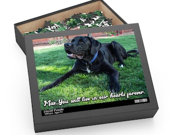 May include: A black and white 500-piece jigsaw puzzle featuring a black dog lying on green grass. The puzzle box has the text "Max... You will live in our hearts forever." and "16x20 Puzzle 500 pcs Ages 9+"